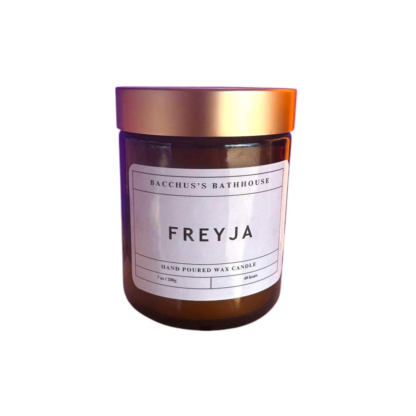 A candle in an amber glass container with a gold lid and white label